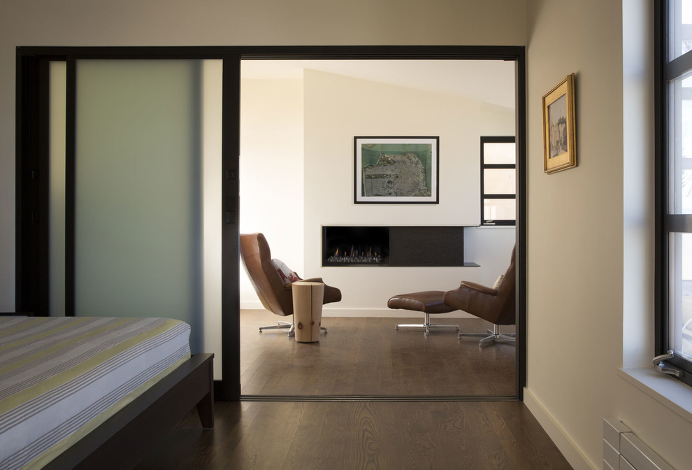 Modelo de salón abierto contemporáneo de tamaño medio con paredes beige, suelo de madera en tonos medios, todas las chimeneas y marco de chimenea de metal