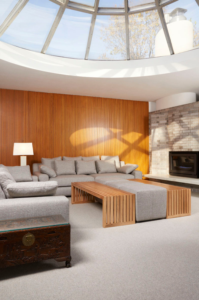 Стильный дизайн: открытая гостиная комната в стиле ретро с ковровым покрытием, стандартным камином, фасадом камина из кирпича и акцентной стеной - последний тренд