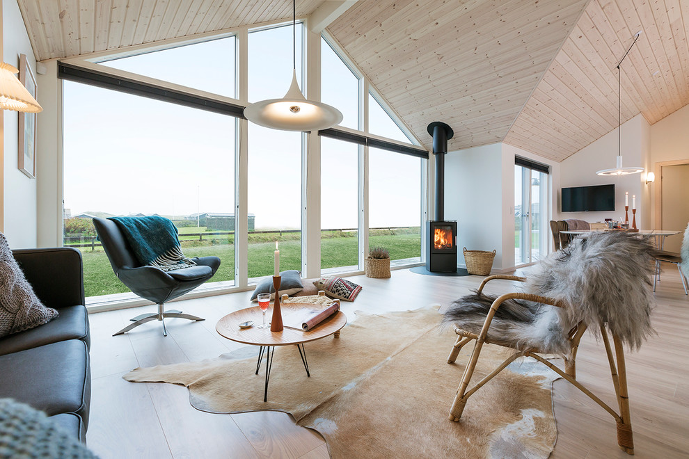 Example of a mid-sized danish formal and open concept painted wood floor living room design in Aarhus with white walls, a wood stove and a wall-mounted tv