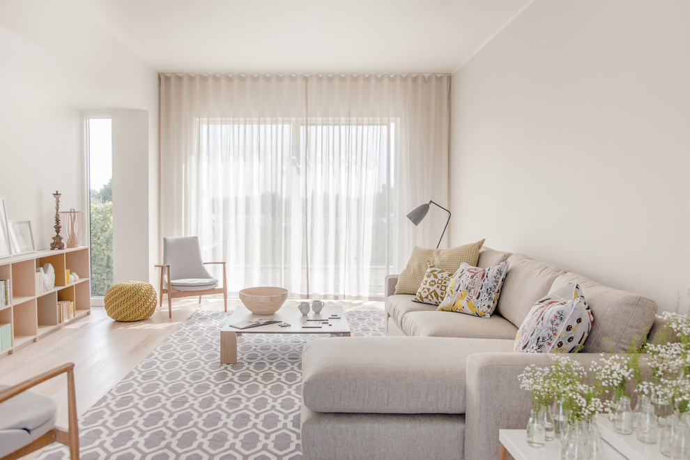 Example of a large trendy light wood floor and beige floor living room design in Other with white walls, no fireplace and no tv