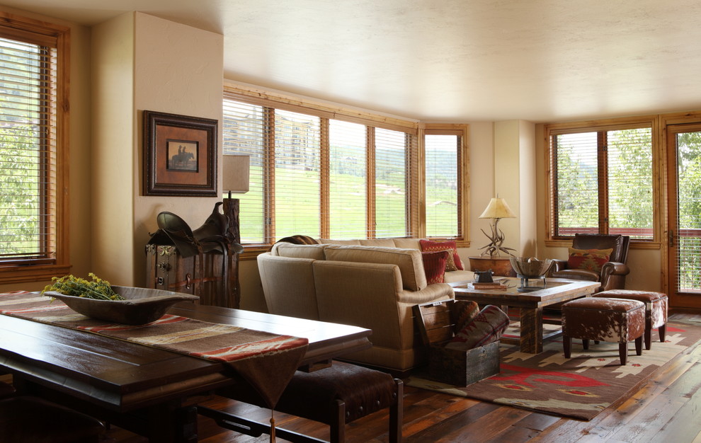 Diseño de salón abierto rural de tamaño medio con paredes beige y suelo de madera en tonos medios