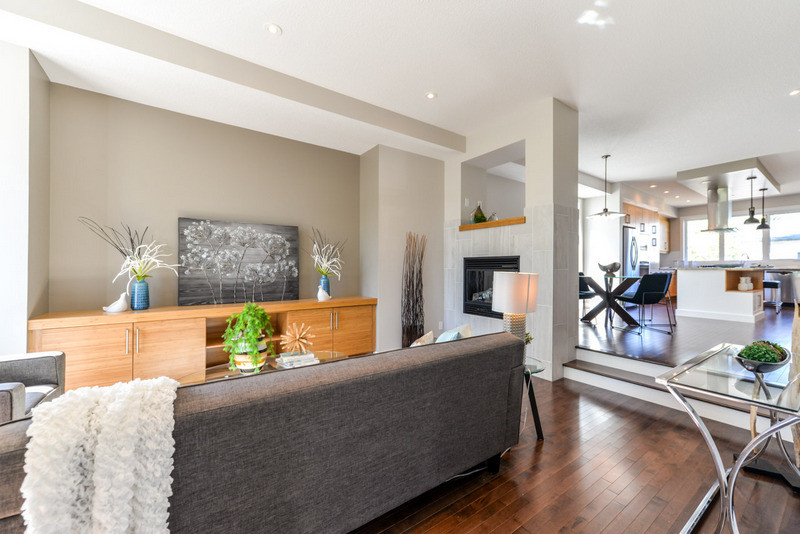 Kleines, Fernseherloses, Offenes Modernes Wohnzimmer mit grauer Wandfarbe, dunklem Holzboden und Tunnelkamin in Calgary