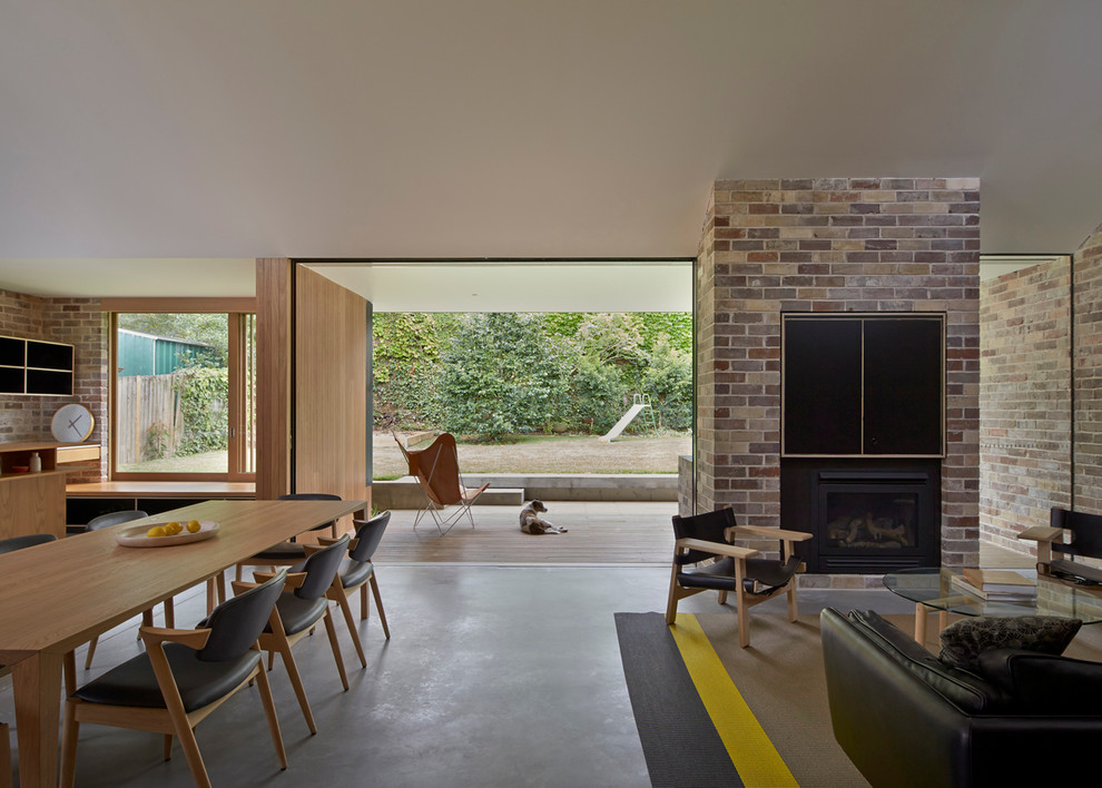 Exemple d'un salon tendance de taille moyenne et ouvert avec sol en béton ciré, une cheminée standard, un manteau de cheminée en brique et un téléviseur dissimulé.
