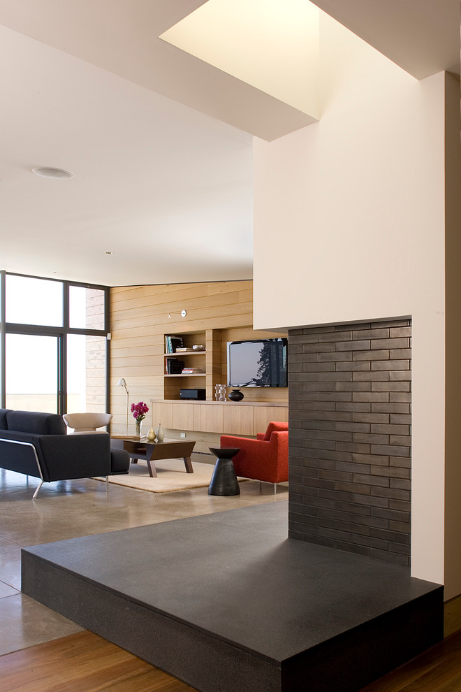 Example of a large trendy open concept concrete floor living room design in San Francisco with white walls, a standard fireplace, a tile fireplace and a media wall