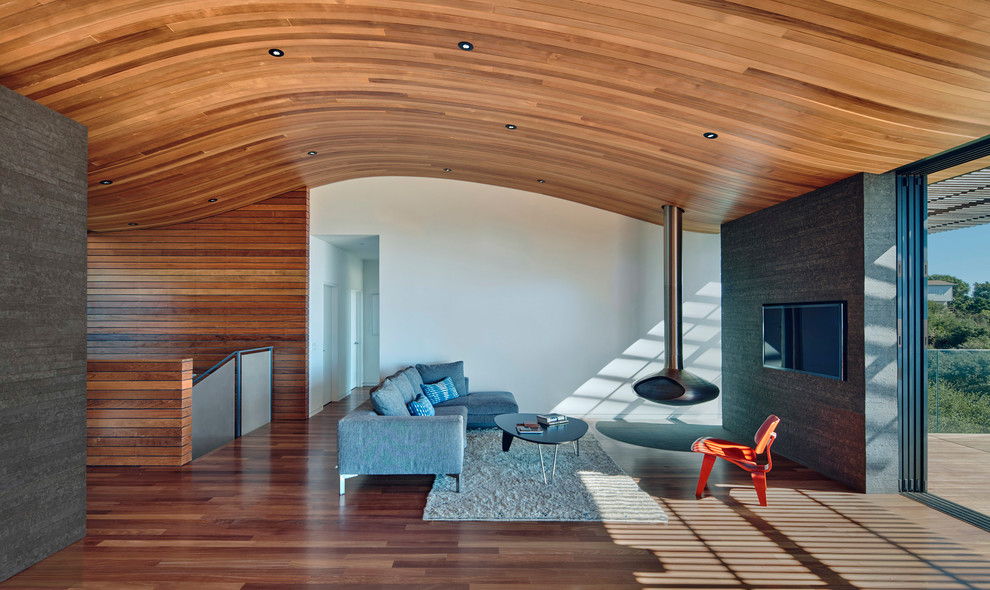 Idée de décoration pour un grand salon minimaliste ouvert avec une salle de réception, un mur blanc, un sol en bois brun, cheminée suspendue, un manteau de cheminée en métal et un téléviseur dissimulé.