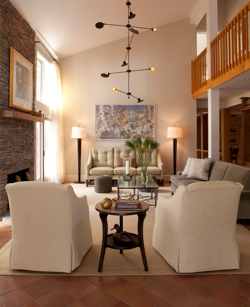 Cette photo montre un salon chic avec un mur beige, tomettes au sol, une cheminée standard et un manteau de cheminée en pierre.
