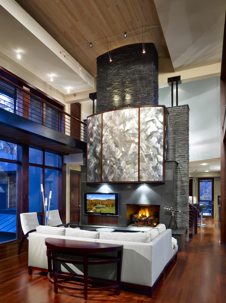 Пример оригинального дизайна: большая открытая гостиная комната в современном стиле с стандартным камином, телевизором на стене, бежевыми стенами, паркетным полом среднего тона и фасадом камина из плитки