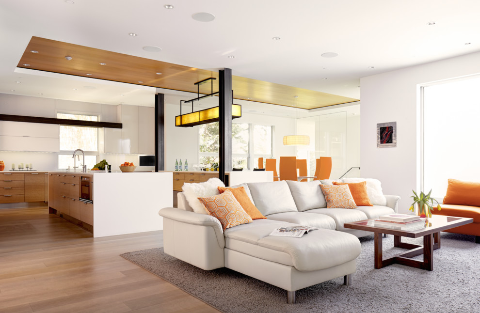 Imagen de salón abierto actual grande con paredes blancas y suelo de madera clara