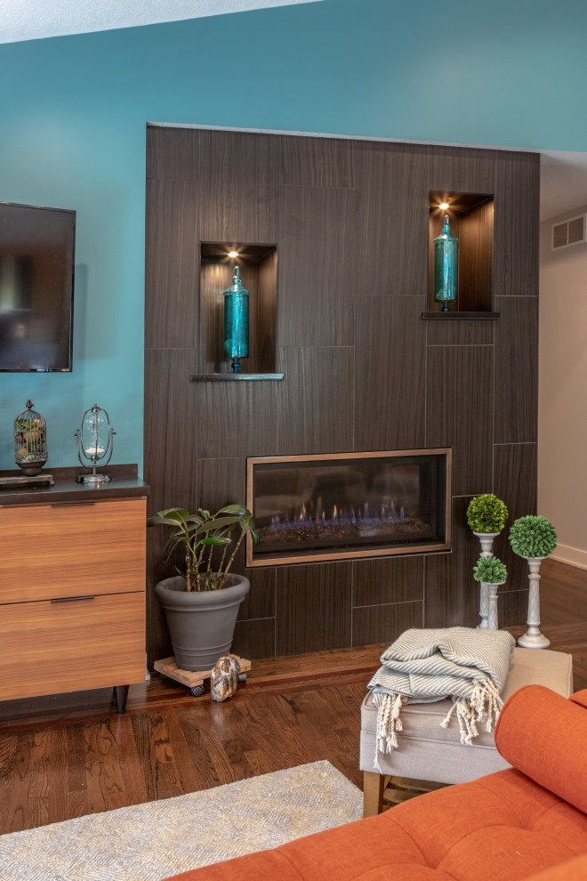 Пример оригинального дизайна: парадная, открытая гостиная комната среднего размера в стиле ретро с синими стенами, темным паркетным полом, горизонтальным камином, фасадом камина из плитки, телевизором на стене и коричневым полом