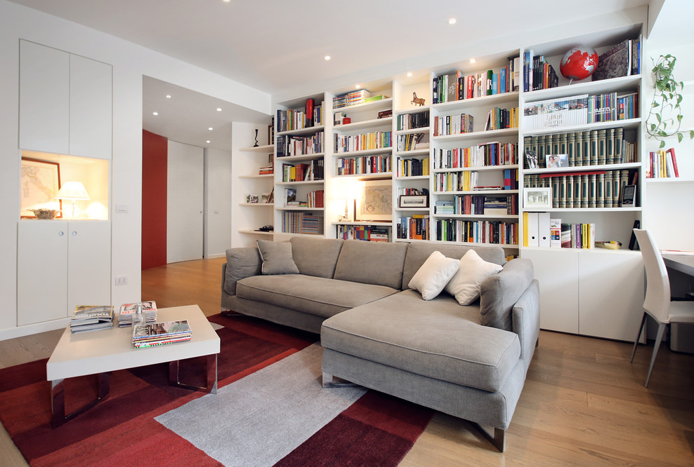 Kleine, Fernseherlose, Offene Moderne Bibliothek mit weißer Wandfarbe und braunem Holzboden in Mailand