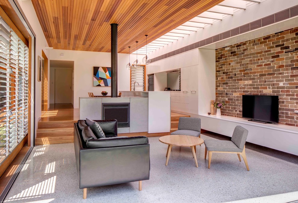 Esempio di un soggiorno minimalista con pavimento in cemento e stufa a legna