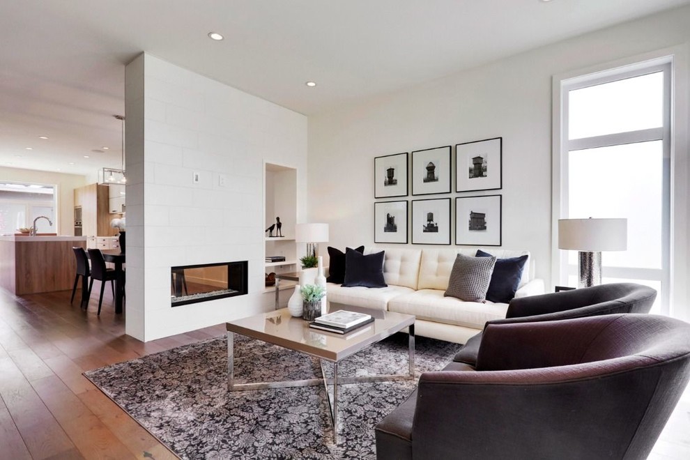 Fernseherloses Modernes Wohnzimmer mit weißer Wandfarbe, braunem Holzboden und Tunnelkamin in Calgary