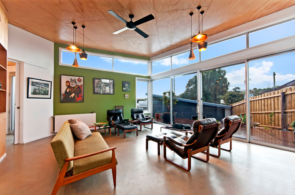 Mittelgroßes, Offenes Modernes Wohnzimmer mit grüner Wandfarbe, TV-Wand, Betonboden und Kaminumrandung aus Backstein in Geelong
