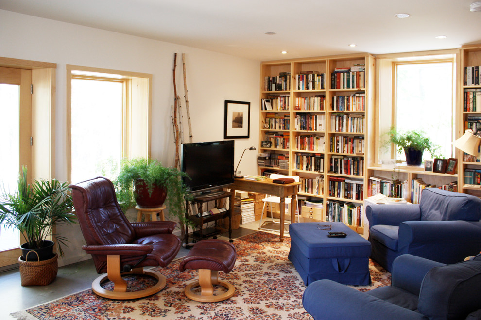 Klassisk inredning av ett vardagsrum, med ett bibliotek, vita väggar, betonggolv, en öppen vedspis, en spiselkrans i tegelsten och en fristående TV