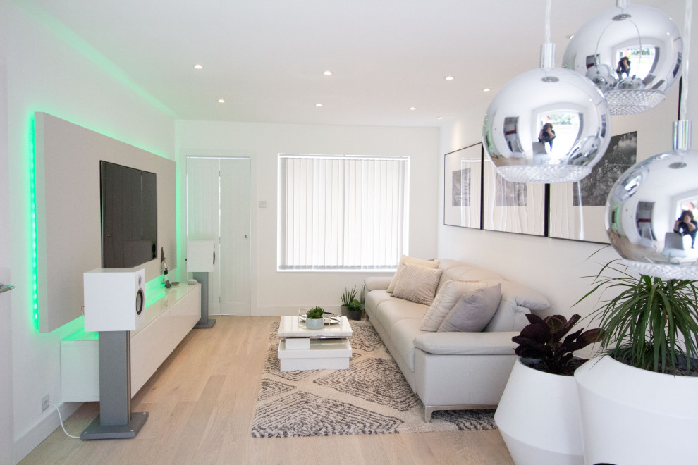 Photo of a small modern formal open plan living room in London with white walls, light hardwood flooring, no fireplace, a concealed tv and beige floors.