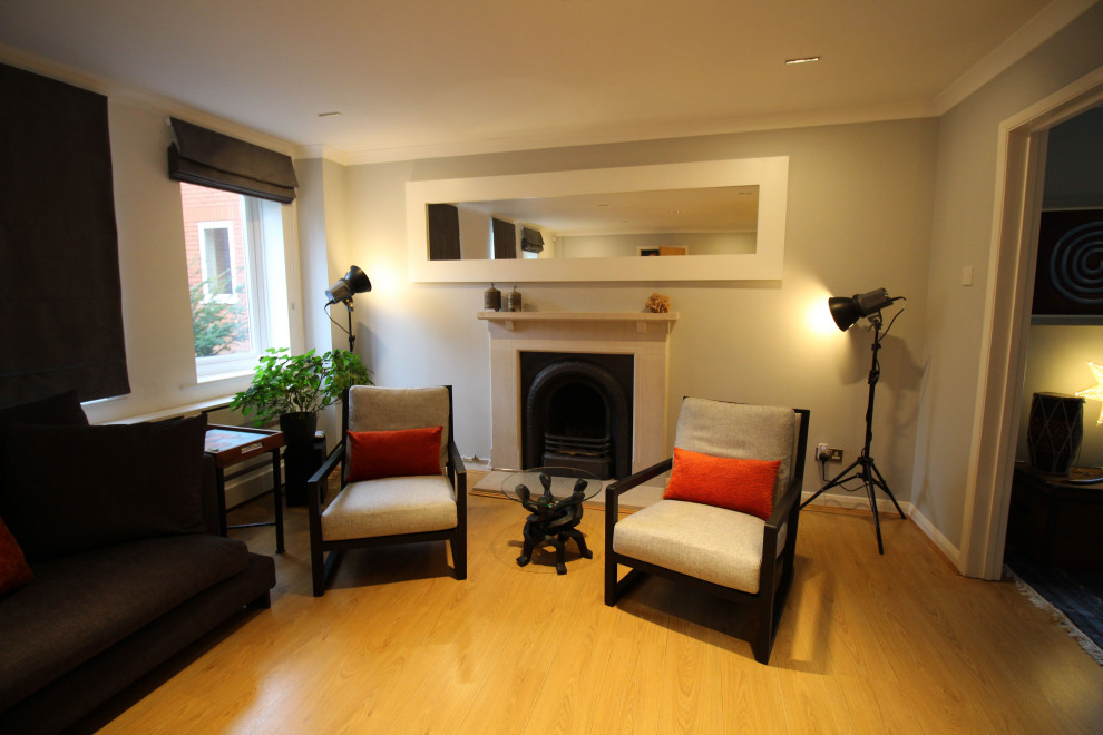 Aménagement d'un salon moderne de taille moyenne et fermé avec une salle de réception, un mur gris, sol en stratifié, une cheminée standard, un manteau de cheminée en pierre, un téléviseur indépendant et un sol jaune.