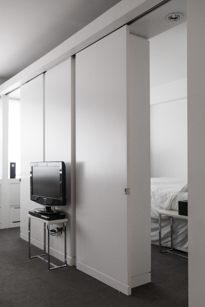 Пример оригинального дизайна: маленькая открытая гостиная комната в современном стиле с белыми стенами, ковровым покрытием и отдельно стоящим телевизором для на участке и в саду