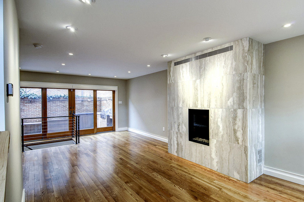 На фото: открытая гостиная комната среднего размера в современном стиле с серыми стенами, паркетным полом среднего тона, стандартным камином, фасадом камина из плитки и коричневым полом