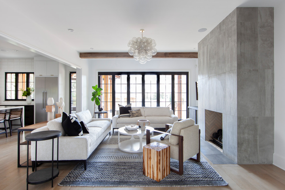Inspiration for a contemporary open plan living room in Charlotte with white walls, light hardwood flooring, a standard fireplace and beige floors.