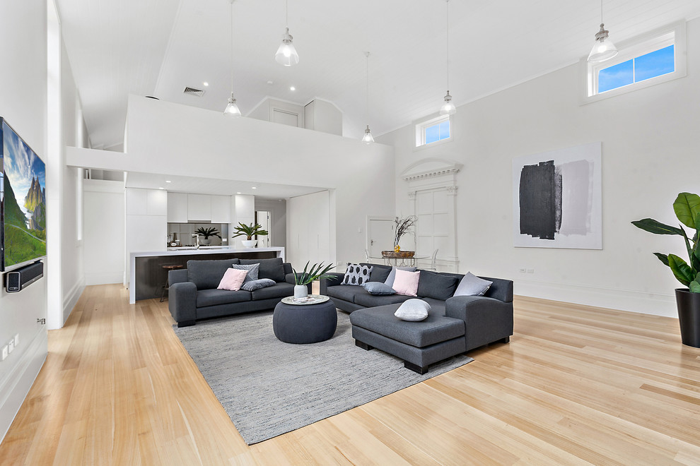 Idee per un soggiorno minimal aperto con pareti bianche, parquet chiaro, TV a parete e pavimento beige