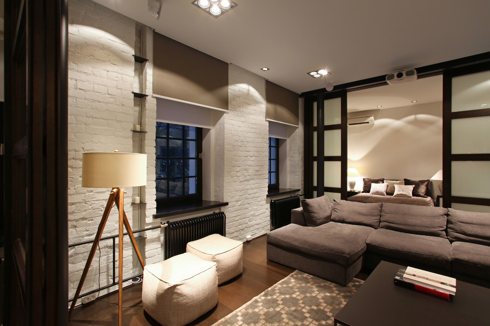 Diseño de salón para visitas abierto industrial pequeño con paredes blancas, suelo de madera en tonos medios y televisor retractable