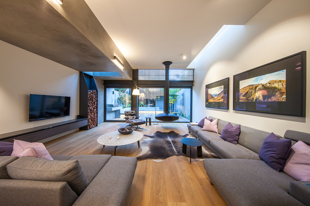 This is an example of a large contemporary open plan living room in Sydney with a hanging fireplace and a wall mounted tv.