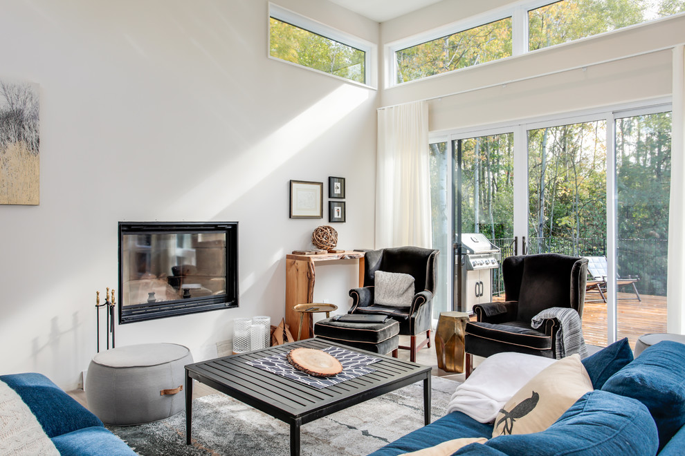 Пример оригинального дизайна: гостиная комната в стиле неоклассика (современная классика) с бежевыми стенами, стандартным камином и синим диваном