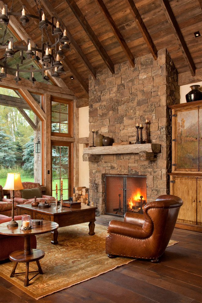 Ejemplo de salón rural con marco de chimenea de piedra, suelo de madera en tonos medios y alfombra