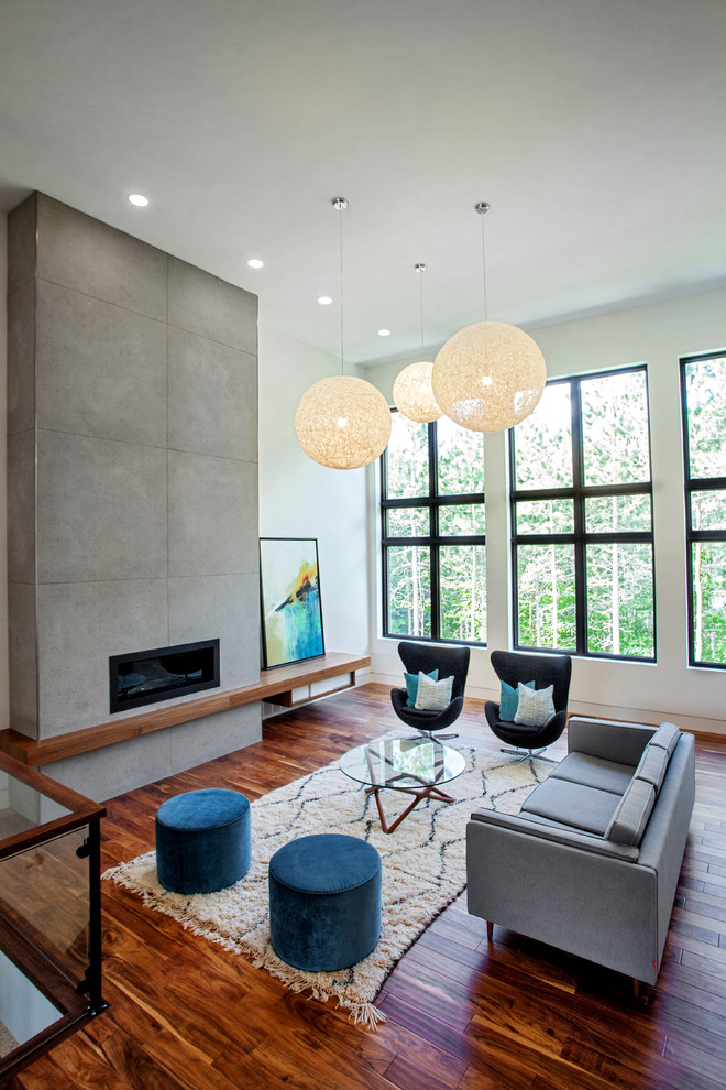 Modelo de salón abierto minimalista grande con paredes blancas, suelo de madera en tonos medios, chimenea lineal, marco de chimenea de baldosas y/o azulejos y pared multimedia