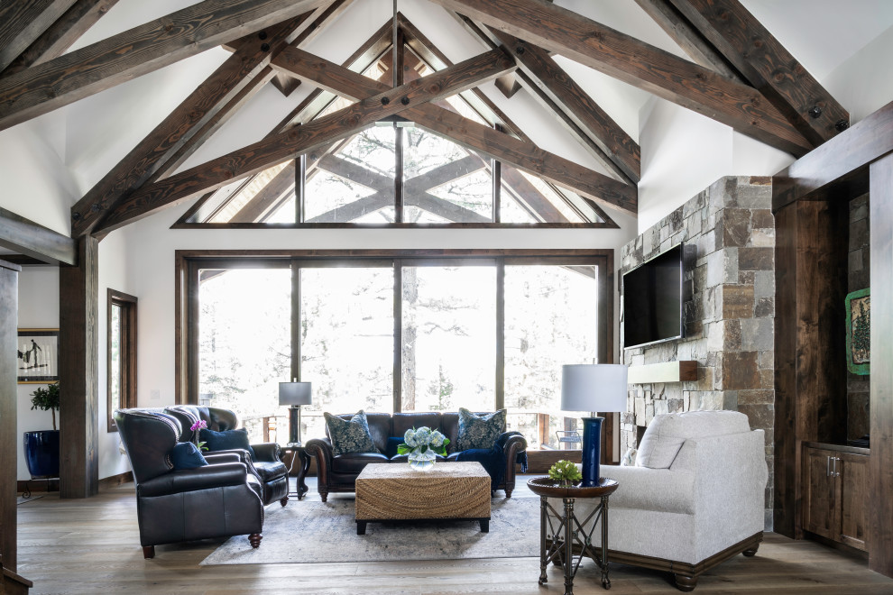 Photo of a large rustic open plan living room in Sacramento with white walls, medium hardwood flooring, a standard fireplace, a stone fireplace surround, a wall mounted tv, brown floors and a vaulted ceiling.