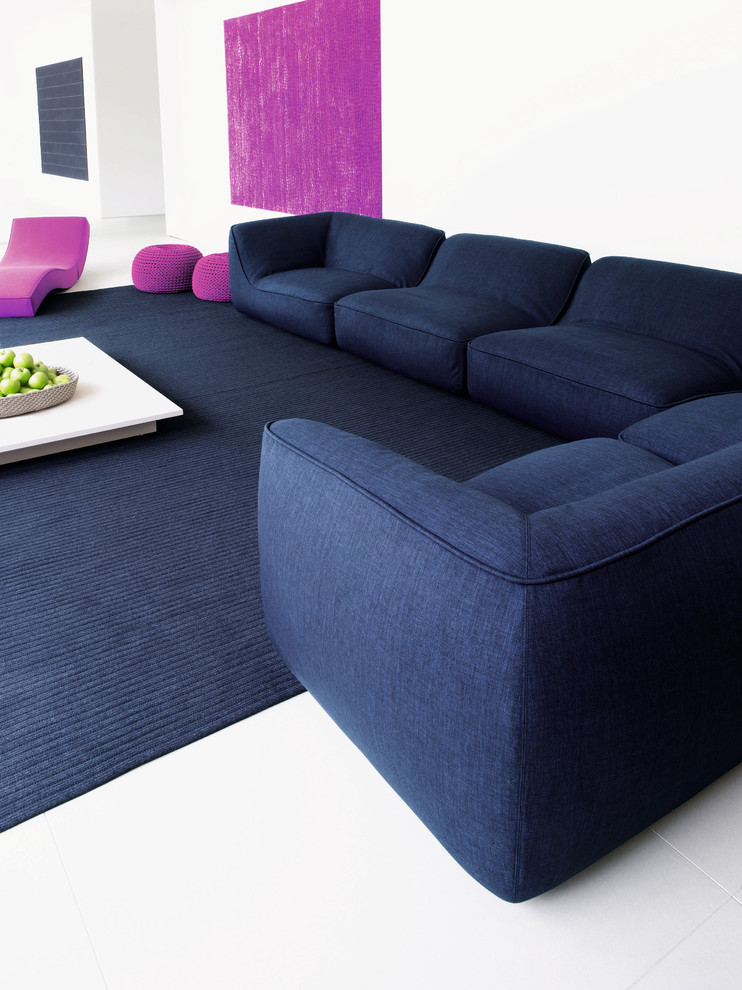 Источник вдохновения для домашнего уюта: гостиная комната в современном стиле с белыми стенами, синим диваном и ковром на полу