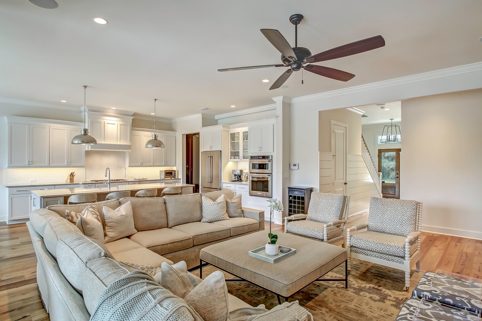 Immagine di un grande soggiorno stile marinaro aperto con pareti bianche, pavimento in legno massello medio, TV a parete e pavimento marrone