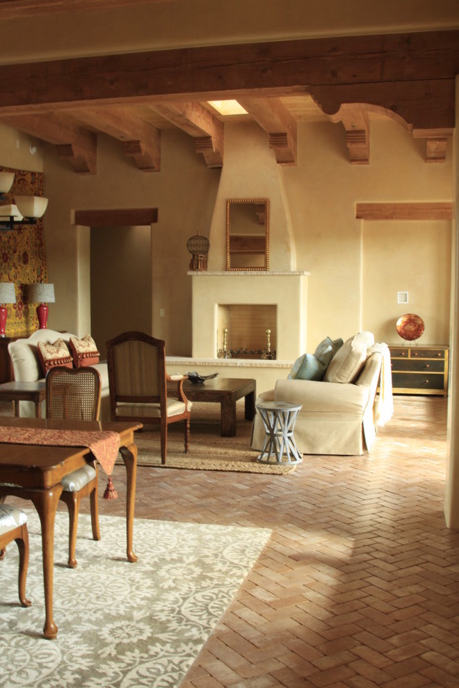 Inspiration for a large formal open plan living room in Albuquerque with beige walls, brick flooring, a standard fireplace, a concrete fireplace surround, no tv, brown floors, exposed beams, a vaulted ceiling and a wood ceiling.
