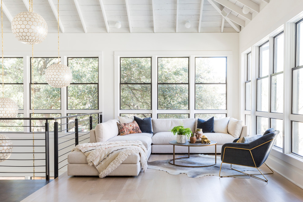 This is an example of a contemporary mezzanine living room in Houston with white walls, light hardwood flooring, no tv and beige floors.