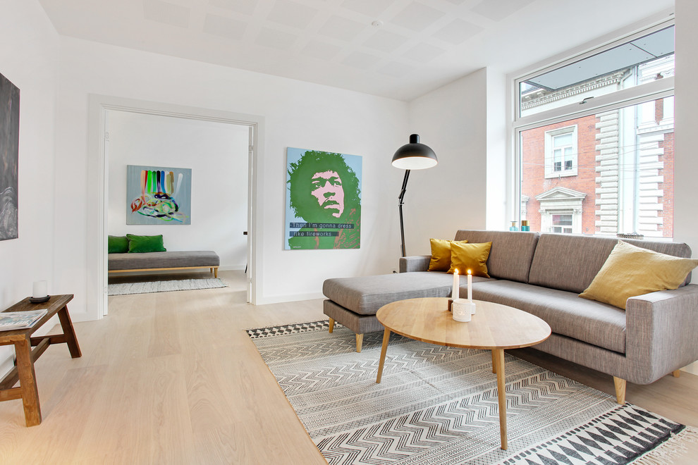 На фото: изолированная гостиная комната среднего размера в скандинавском стиле с светлым паркетным полом, бежевым полом и белыми стенами без камина с