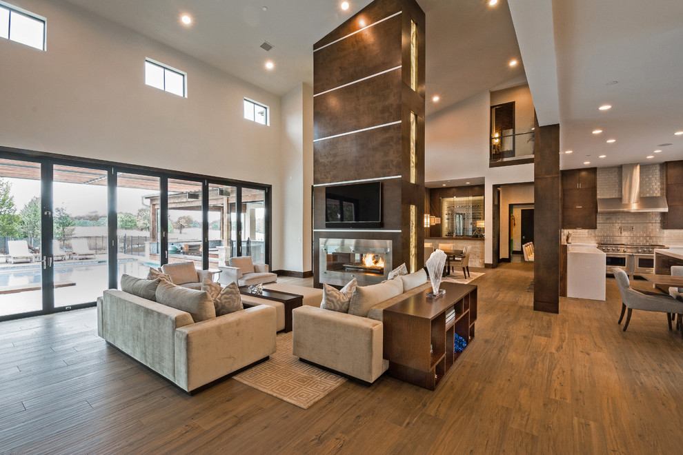 Photo of an expansive contemporary open plan living room in Orange County with grey walls, porcelain flooring, a two-sided fireplace, a metal fireplace surround and brown floors.