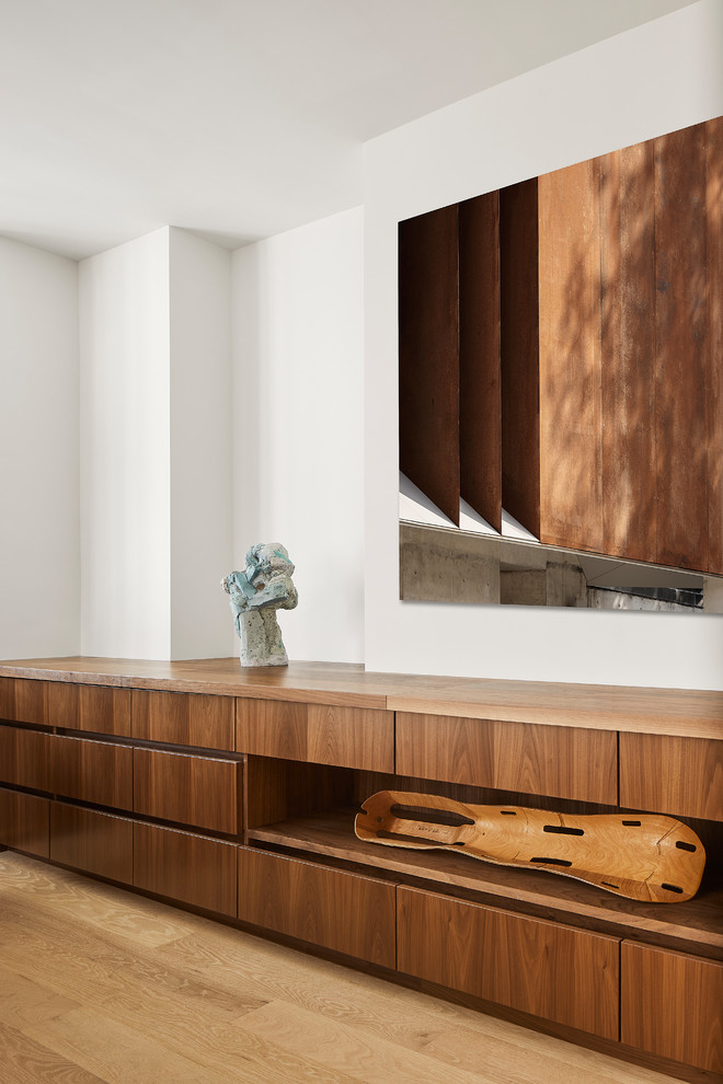Modelo de salón abierto minimalista sin televisor con paredes blancas y suelo de madera clara