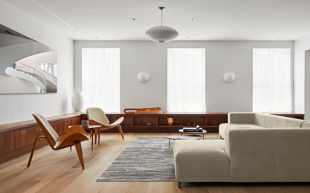 Ejemplo de salón abierto actual con paredes blancas, suelo de madera clara y suelo marrón