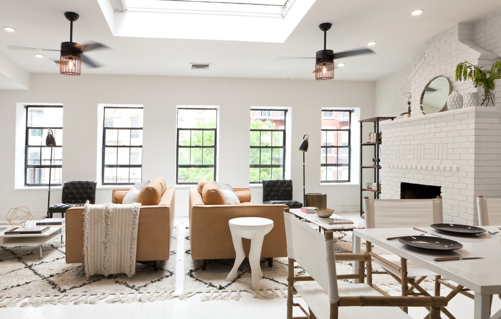 Immagine di un soggiorno design aperto con pareti bianche, pavimento in legno verniciato, camino classico e tappeto