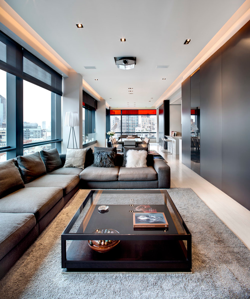 Esempio di un soggiorno design aperto e di medie dimensioni con pareti grigie, parquet chiaro, TV nascosta e pavimento beige