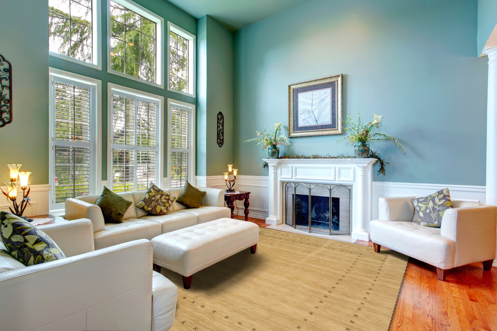 Cette image montre un grand salon traditionnel fermé avec un mur bleu, un sol en bois brun et une cheminée standard.