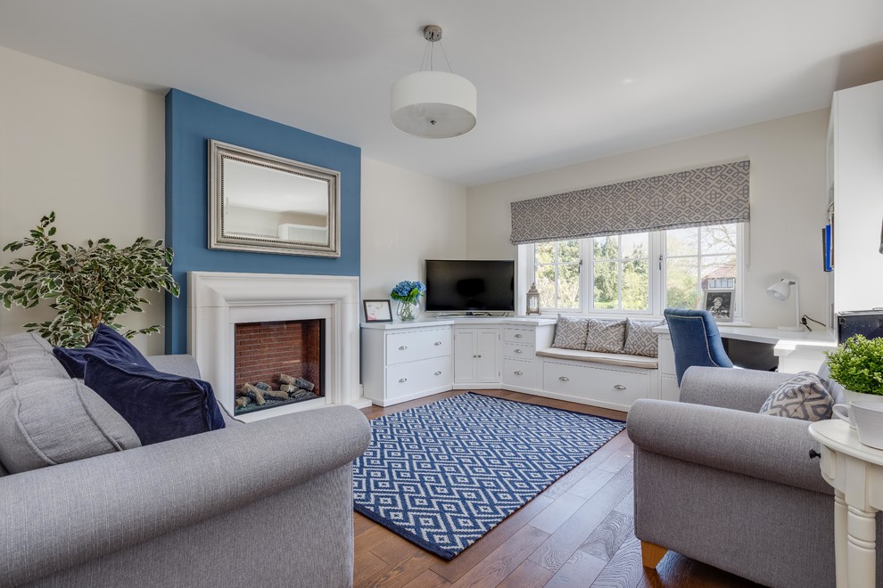 Inspiration pour un salon marin fermé avec un mur bleu, un sol en bois brun, une cheminée standard, un manteau de cheminée en pierre, un téléviseur encastré et un sol marron.