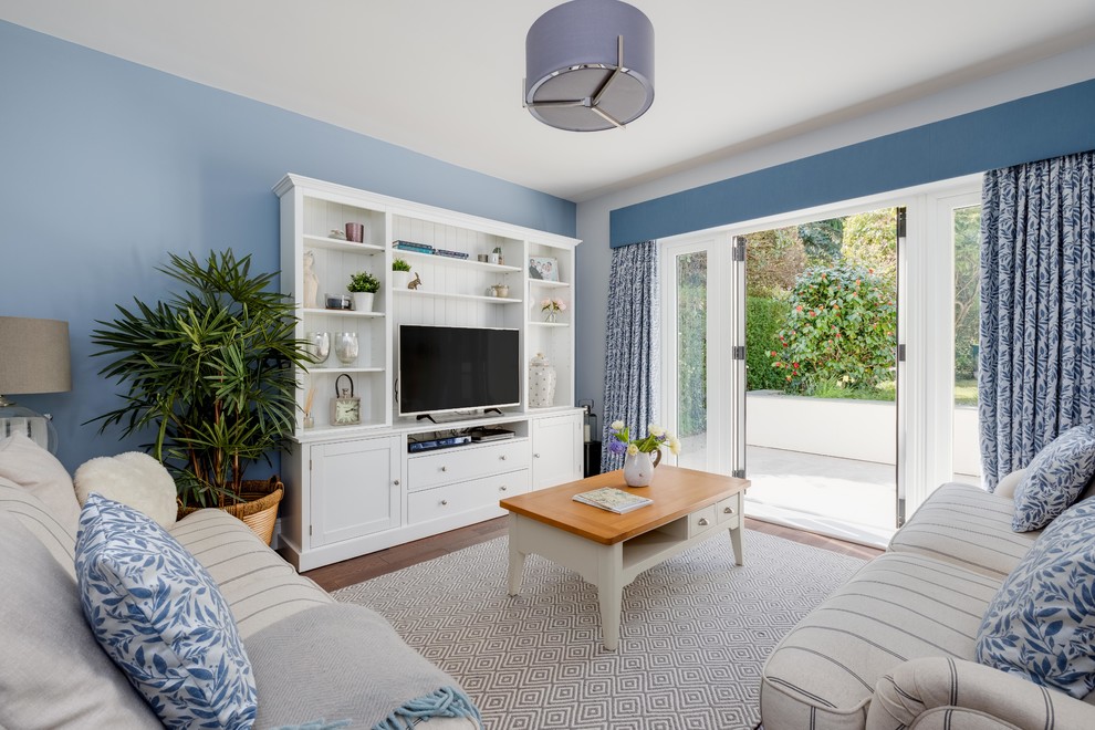 Mittelgroßes, Abgetrenntes Maritimes Wohnzimmer ohne Kamin mit blauer Wandfarbe, braunem Holzboden, freistehendem TV und braunem Boden in West Midlands