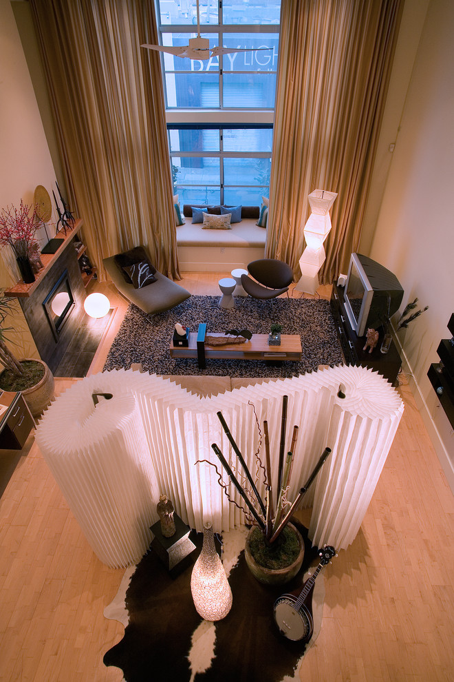 Immagine di un grande soggiorno contemporaneo stile loft con pareti gialle, parquet chiaro, camino classico, cornice del camino piastrellata e TV autoportante