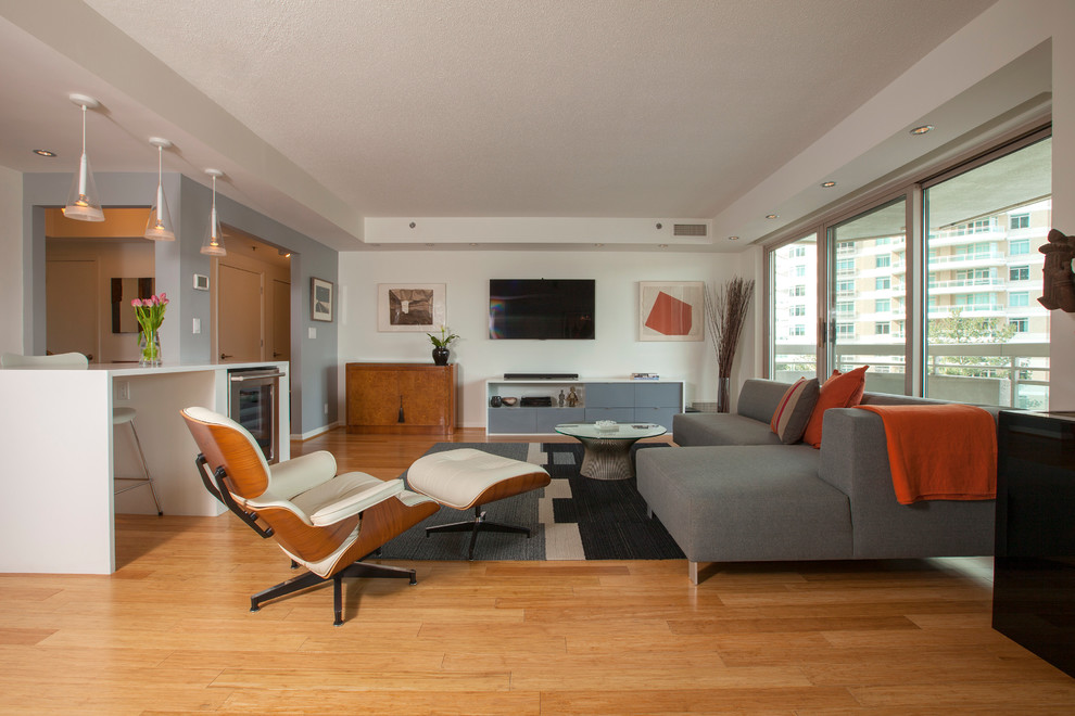 Immagine di un soggiorno design di medie dimensioni e aperto con pareti bianche, pavimento in legno massello medio, nessun camino e TV a parete