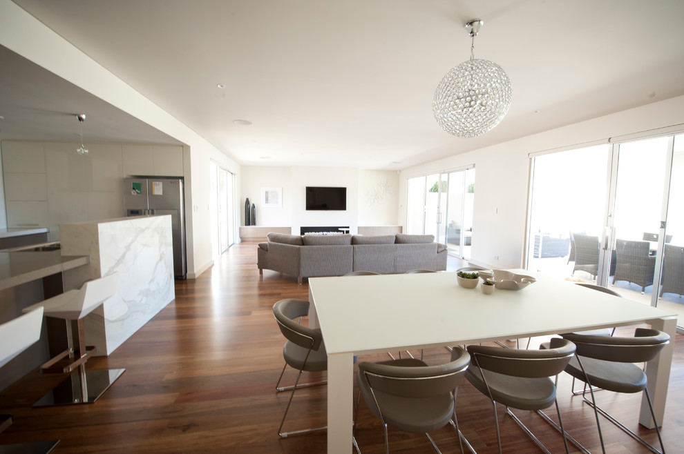 Example of a mid-sized trendy open concept medium tone wood floor living room design in Adelaide with white walls, no fireplace, a concrete fireplace and a wall-mounted tv