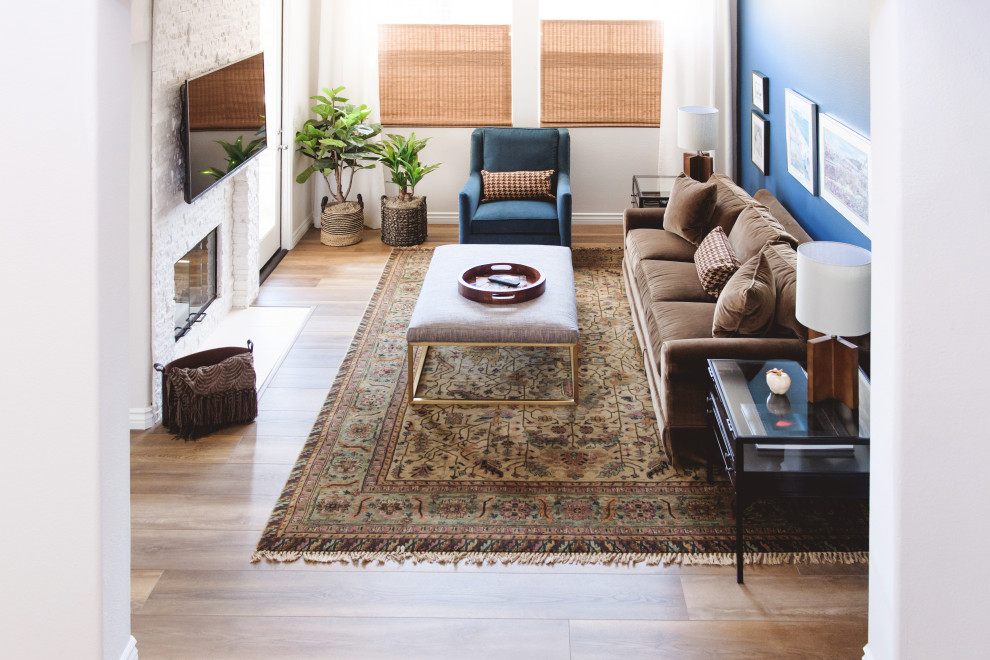 サンディエゴにあるお手頃価格の小さなおしゃれな独立型リビング (青い壁、ラミネートの床、標準型暖炉、積石の暖炉まわり、壁掛け型テレビ、茶色い床) の写真