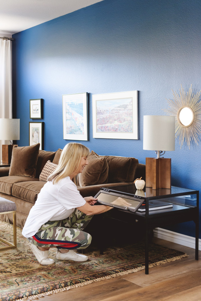 Imagen de salón cerrado pequeño con paredes azules, suelo laminado, todas las chimeneas, piedra de revestimiento, televisor colgado en la pared y suelo marrón