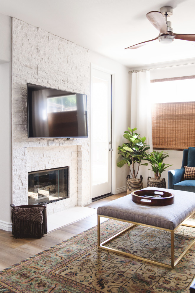 На фото: маленькая изолированная гостиная комната с синими стенами, полом из ламината, стандартным камином, фасадом камина из каменной кладки, телевизором на стене и коричневым полом для на участке и в саду с