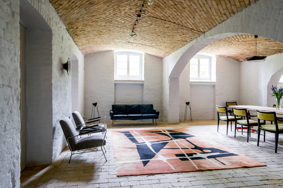 Foto de salón tipo loft bohemio de tamaño medio sin televisor y chimenea con paredes blancas, suelo de ladrillo, suelo beige y arcos